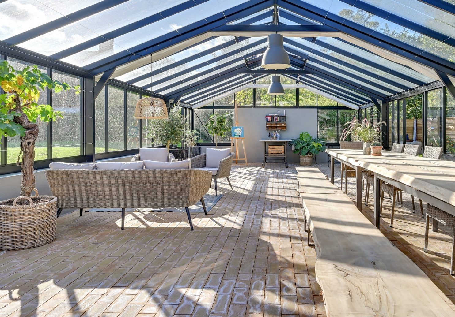 A bright glass-roofed Nordic Garden Building with long tables and plants