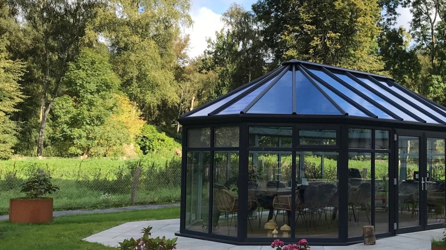 A dark-framed glazed pavilion among trees
