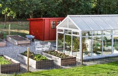 A white garden building beside raised vegetable beds